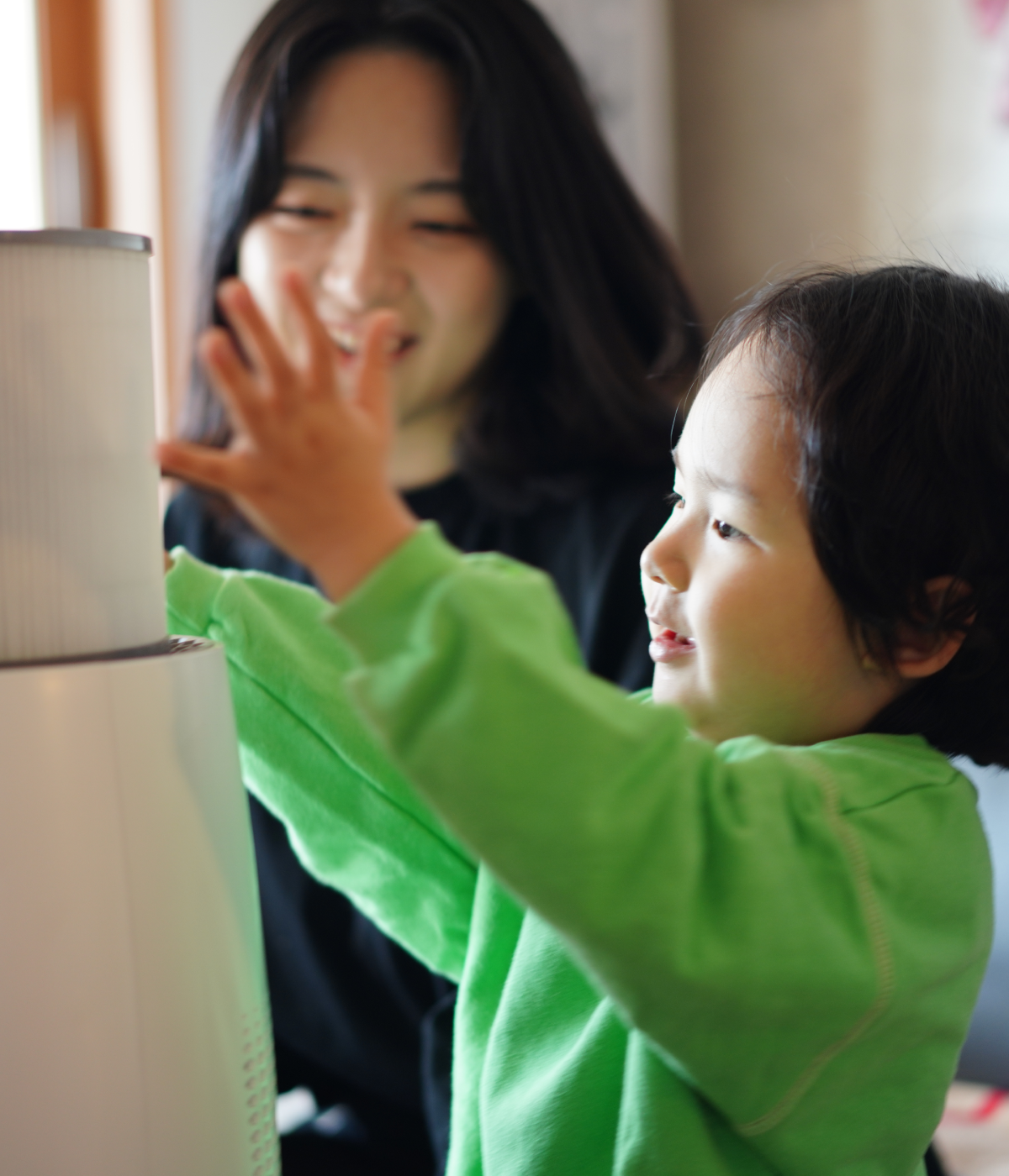 Mother smiling as young daughter loads nano air filter into Zenwell appliance