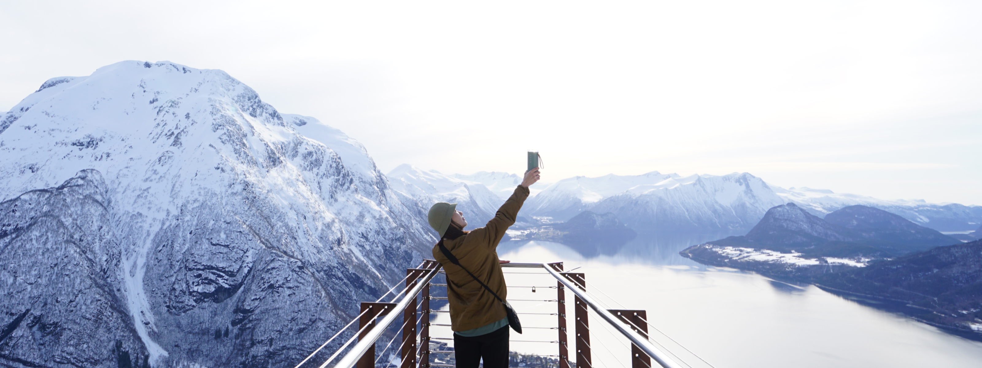 Woman raising Zenwell Air Doctor upwards towards the sky while standing atop a alpine observation deck