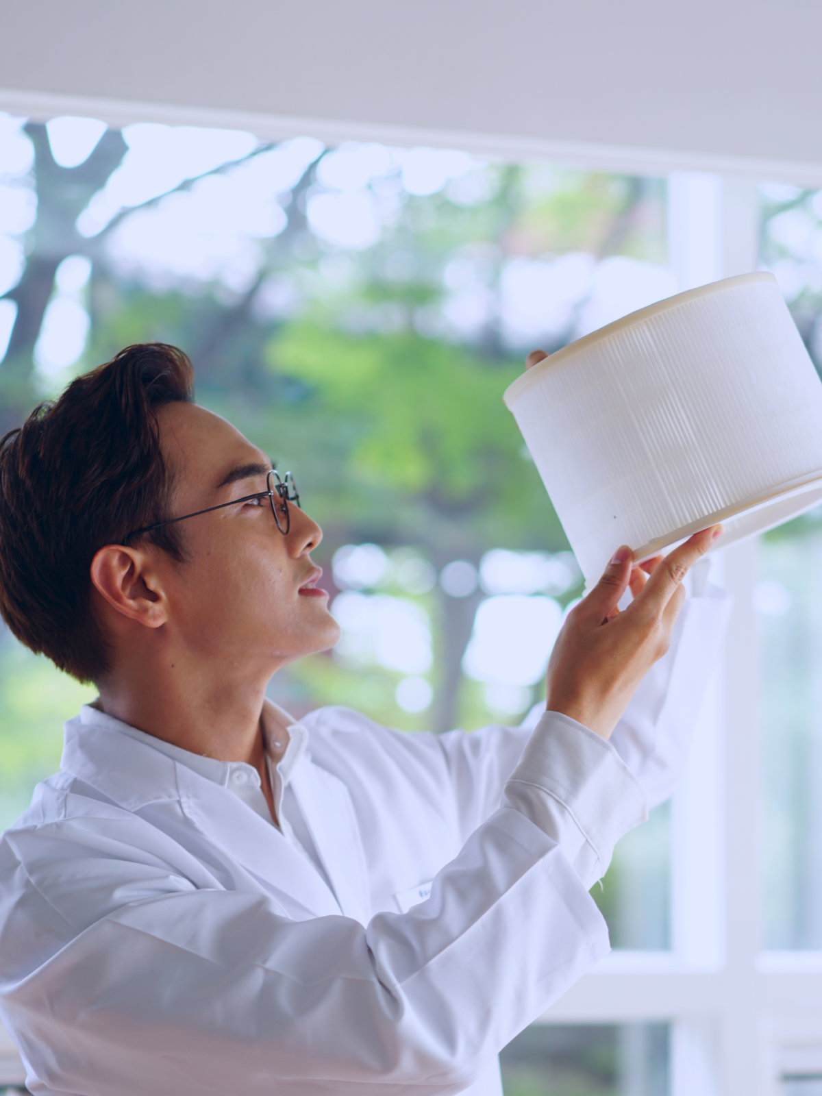 Man in labcoat holding up and examining Zenwell nano air filter