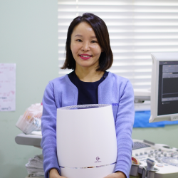 Woman smiling and holding Zenwell appliance in hospital room