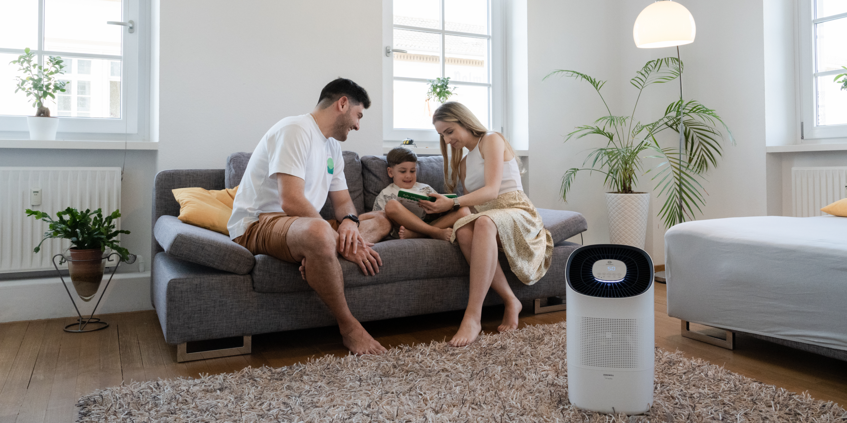 Parents reading book with son on couch next to Zenwell Super Air Purifier and Humidifier