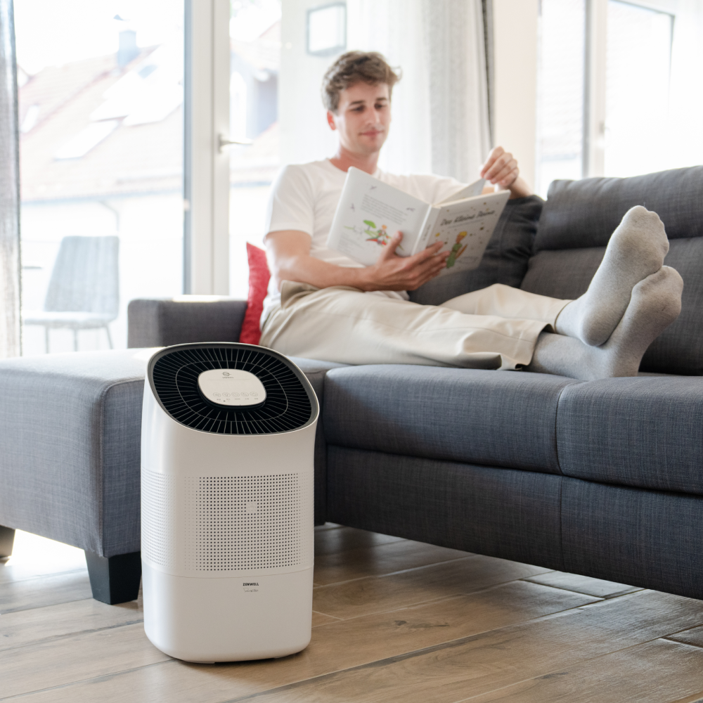 Super Air Purifier and Humidifier Smart on living room floor with man reading on couch in background