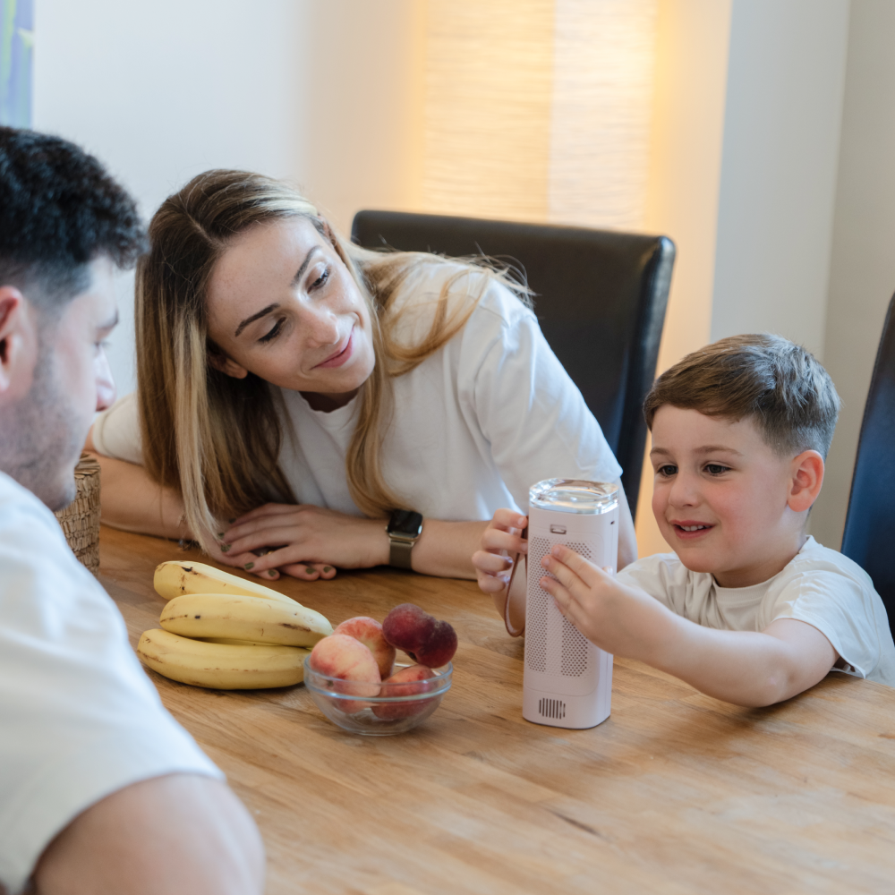 Toddler playing with Baby Safe Air Doctor at dining table with parents