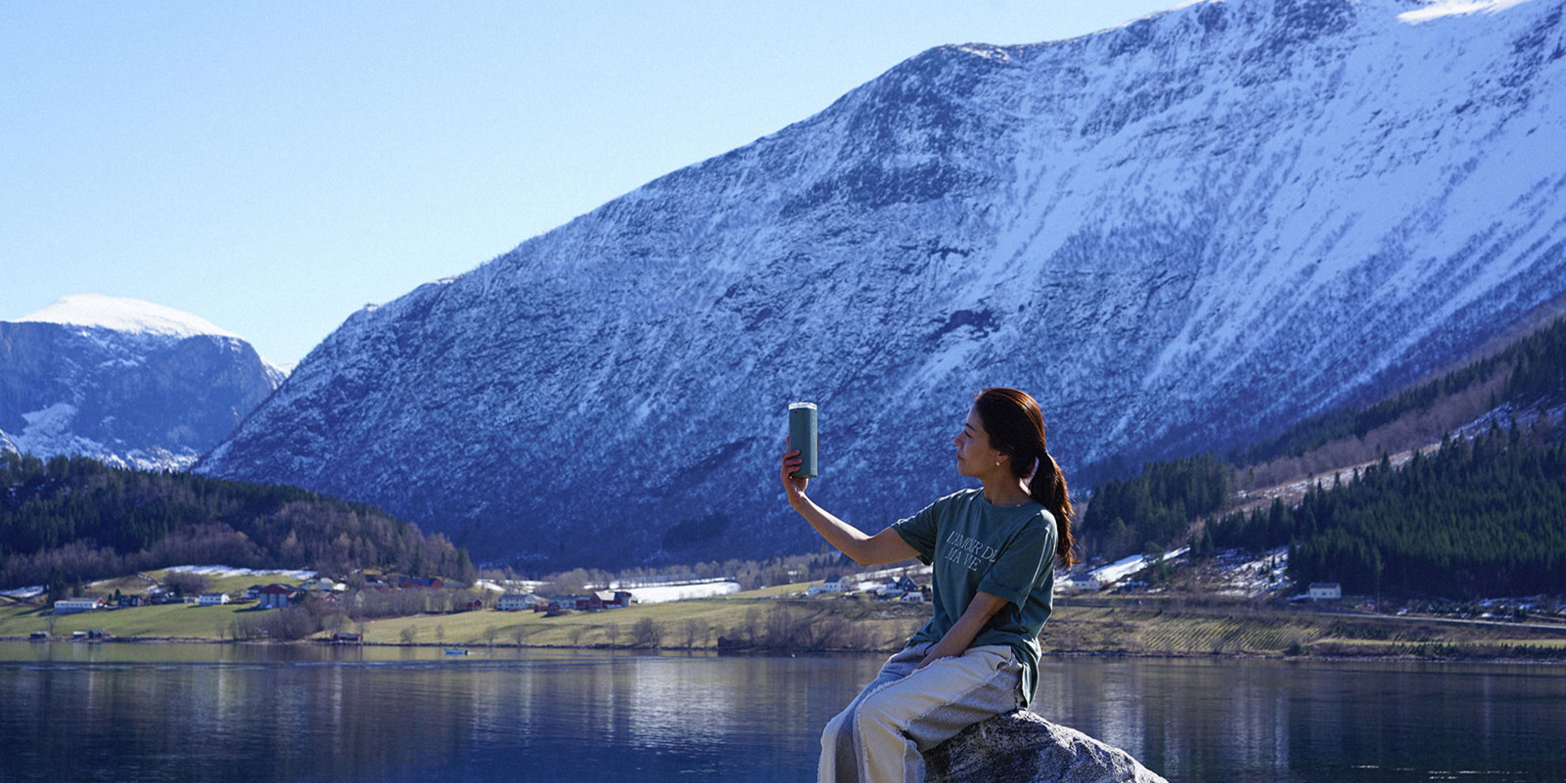 Woman holding and admiring Air Doctor portable purifier in front of alpine lake