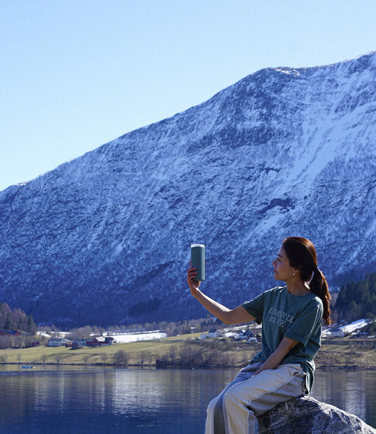 Woman holding and admiring Air Doctor portable purifier in front of alpine lake