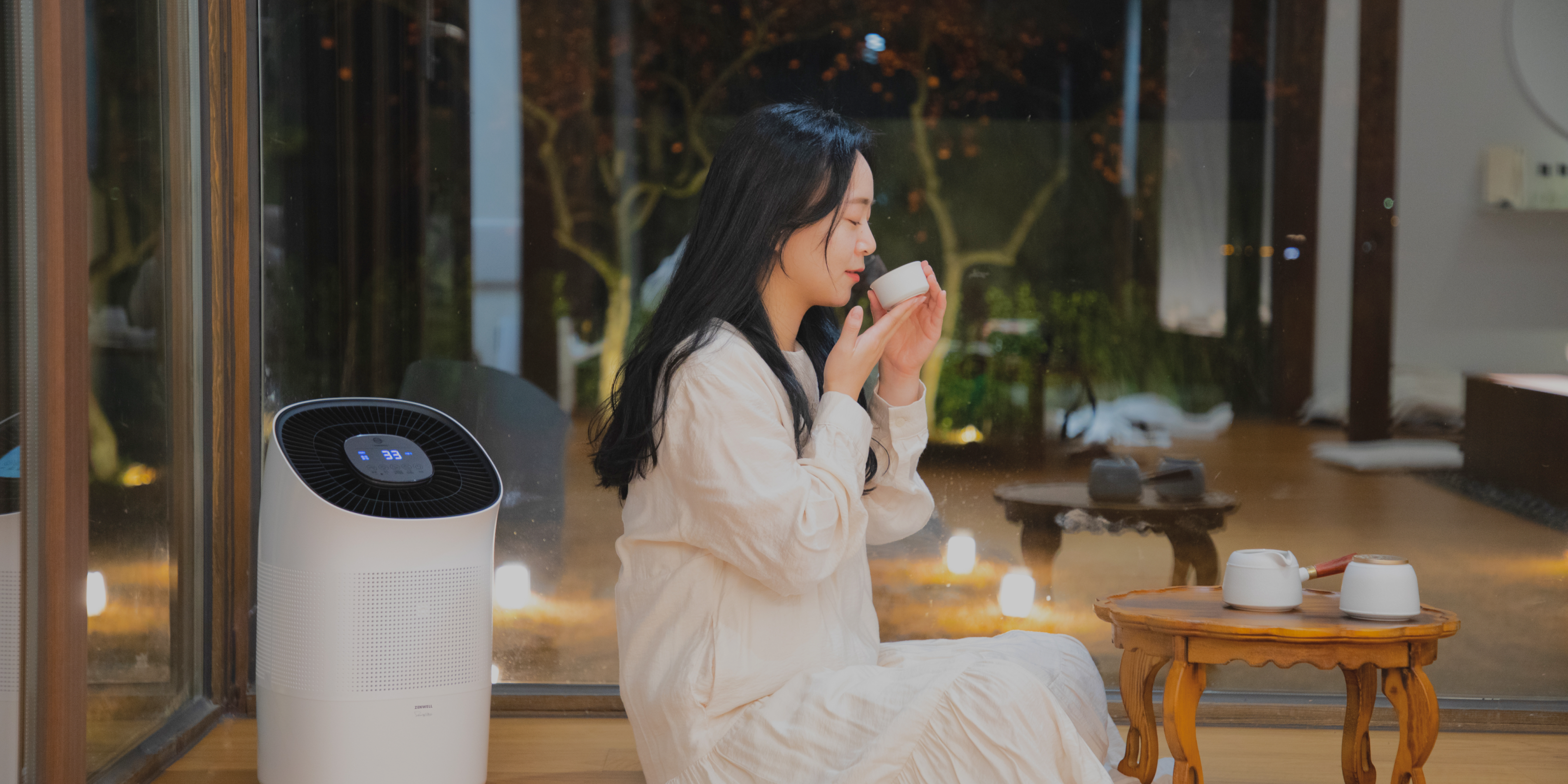 Woman sitting and peacefully drinking tea while Zenwell appliance runs in background