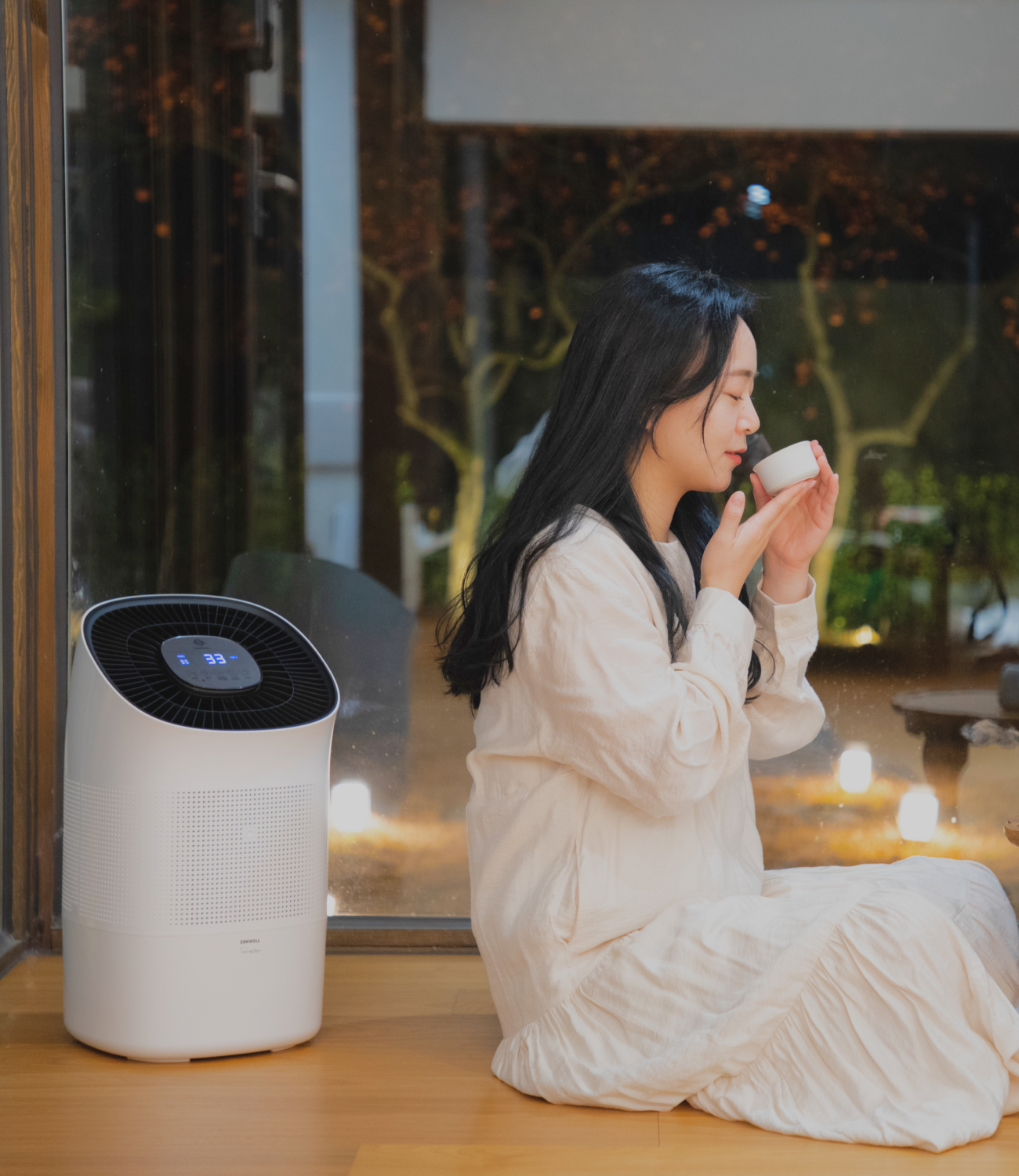 Woman sitting and peacefully drinking tea while Zenwell appliance runs in background