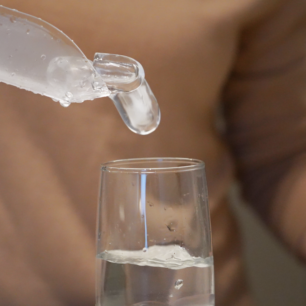 Person pouring crystal clear ice from the Dokdo Freeze into a glass of ice water